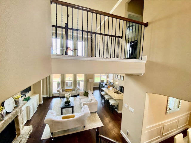 3724 Estates Way, Mckinney, TX 75072 - living area featuring wood finished floors, a fireplace with raised hearth, baseboards, and a high ceiling