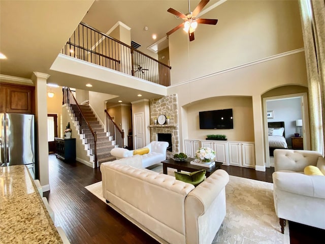 3724 Estates Way, Mckinney, TX 75072 - living area with a fireplace, a ceiling fan, wood finished floors, a towering ceiling, and stairway