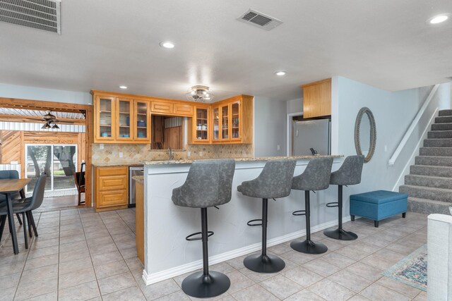 231 Granada Calle St, Granbury, TX 76049 - kitchen with stainless steel appliances, recessed lighting, light stone countertops, a breakfast bar, and tasteful backsplash