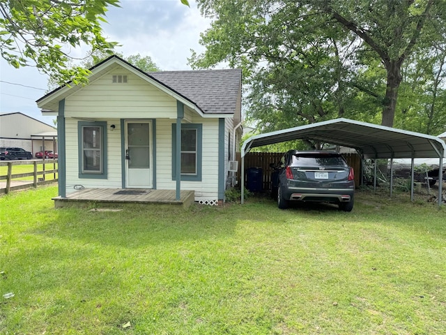 bungalow with a front yard, fence, roof with shingles, and a carport