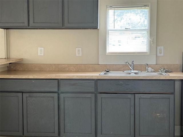 kitchen featuring light countertops, gray cabinetry, and a sink