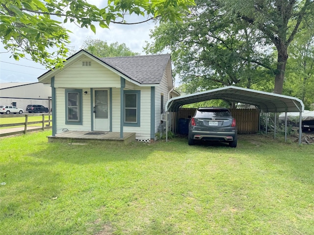 bungalow featuring a detached carport, roof with shingles, fence, and a front lawn