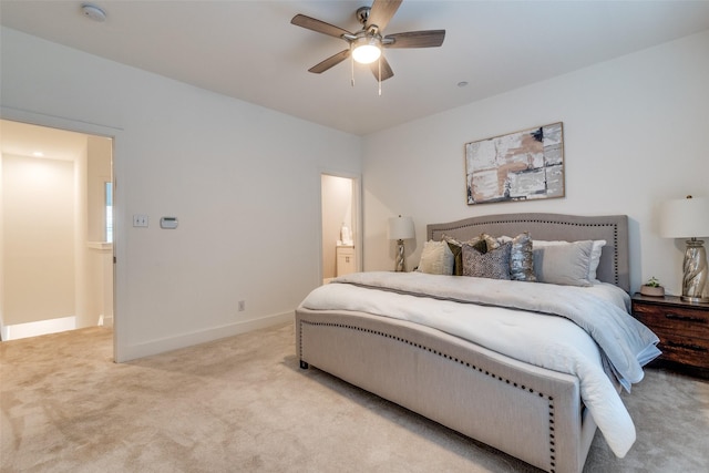 bedroom with a ceiling fan, baseboards, light colored carpet, and ensuite bathroom