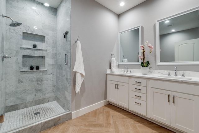 full bath featuring double vanity, visible vents, a stall shower, a sink, and baseboards