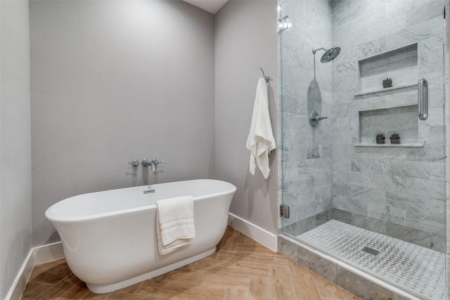 bathroom featuring baseboards, a freestanding bath, and a shower stall