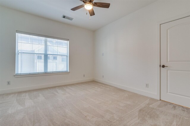 spare room featuring baseboards, light carpet, a ceiling fan, and visible vents
