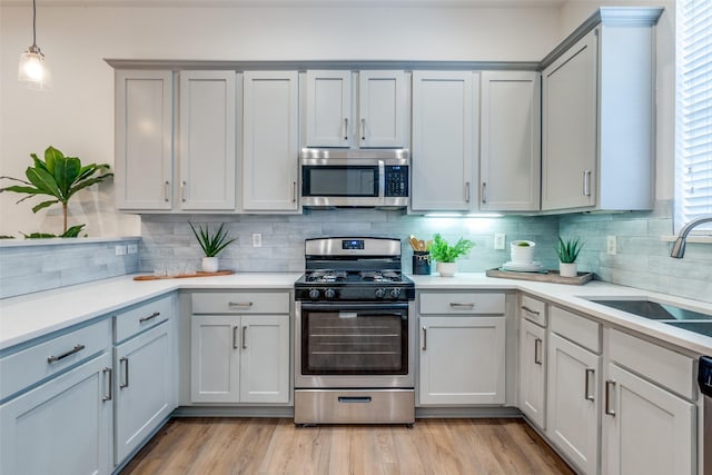 kitchen with backsplash, stainless steel appliances, gray cabinetry, and light countertops