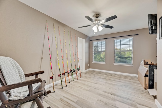 living area featuring light wood-style floors, baseboards, and a ceiling fan