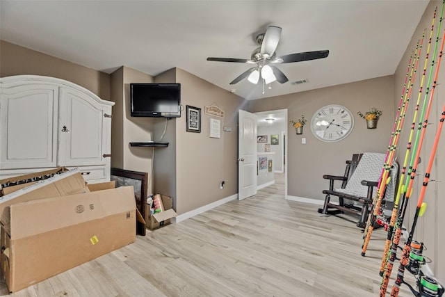 interior space with a ceiling fan, baseboards, visible vents, and light wood finished floors