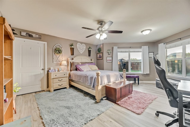 bedroom featuring baseboards, a ceiling fan, and light wood-style flooring