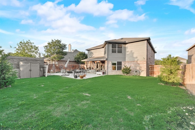 rear view of property with brick siding, a storage shed, a fenced backyard, a patio area, and a lawn