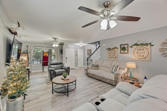 living room with ceiling fan, wood finished floors, and stairway