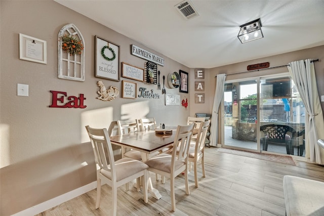 dining space featuring light wood-style flooring and visible vents