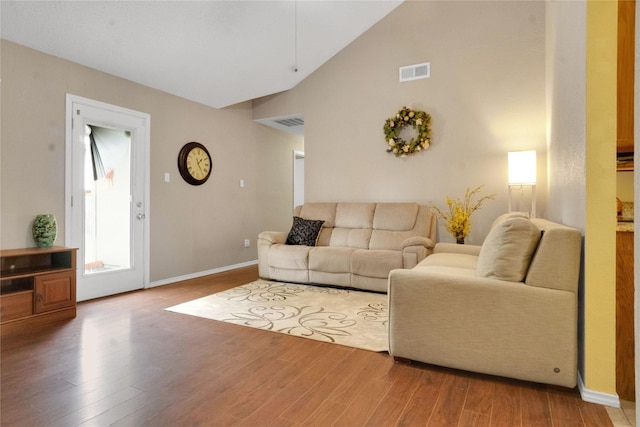 living area with baseboards, visible vents, and wood finished floors
