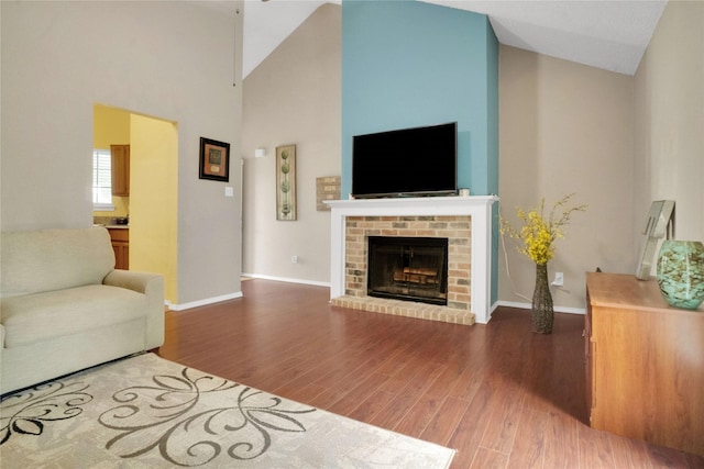living area with high vaulted ceiling, baseboards, a fireplace, and wood finished floors