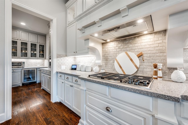 kitchen with stainless steel gas cooktop, beverage cooler, glass insert cabinets, and backsplash
