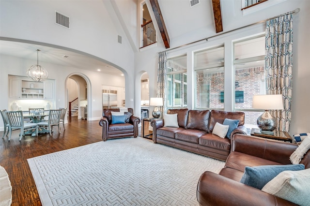 living area with visible vents, a high ceiling, dark wood-style floors, arched walkways, and a notable chandelier