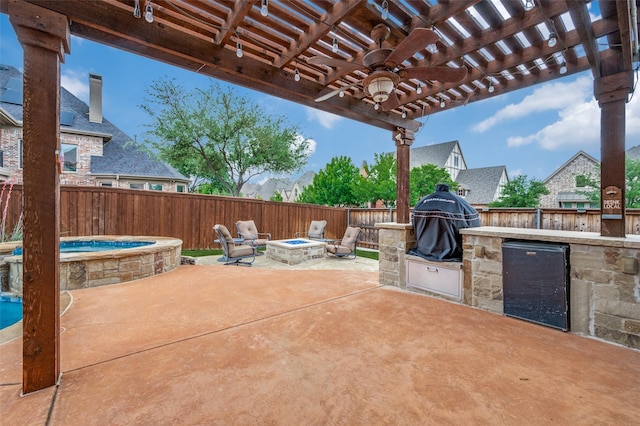 view of patio with an outdoor fire pit, an outdoor kitchen, a fenced backyard, an outdoor hot tub, and a ceiling fan