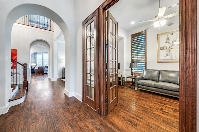 entryway with wood finished floors, baseboards, ceiling fan, french doors, and arched walkways