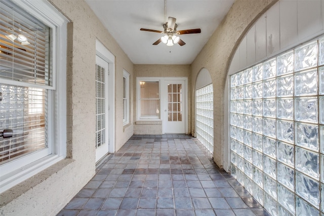 unfurnished sunroom featuring a ceiling fan