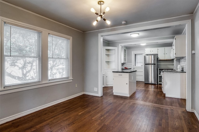 kitchen featuring freestanding refrigerator, dark countertops, dark wood-type flooring, white cabinets, and a notable chandelier