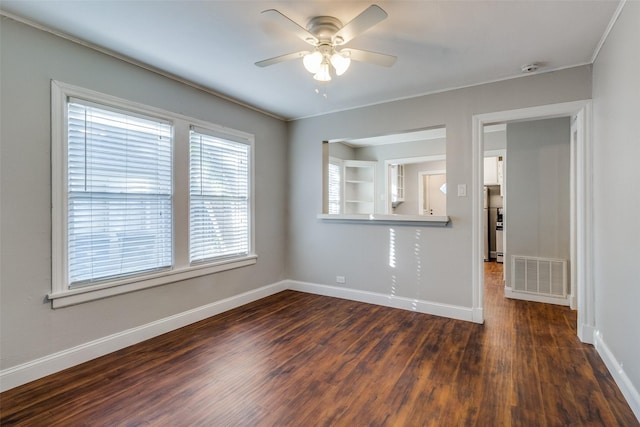 spare room featuring ceiling fan, visible vents, crown molding, baseboards, and dark wood-type flooring