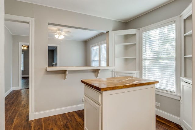 interior space featuring wood counters, baseboards, and white cabinetry
