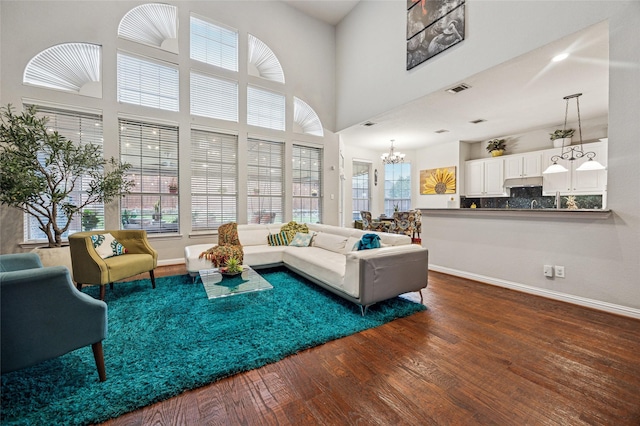 living room featuring an inviting chandelier, baseboards, wood finished floors, and visible vents