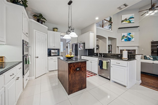 kitchen featuring visible vents, a peninsula, open floor plan, a center island, and appliances with stainless steel finishes