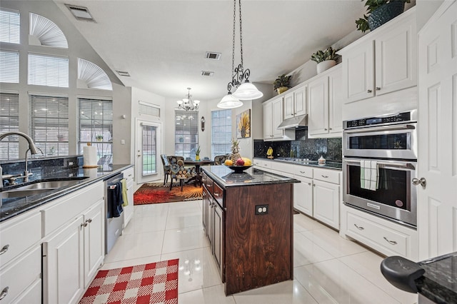 kitchen featuring an inviting chandelier, a sink, stainless steel appliances, under cabinet range hood, and visible vents