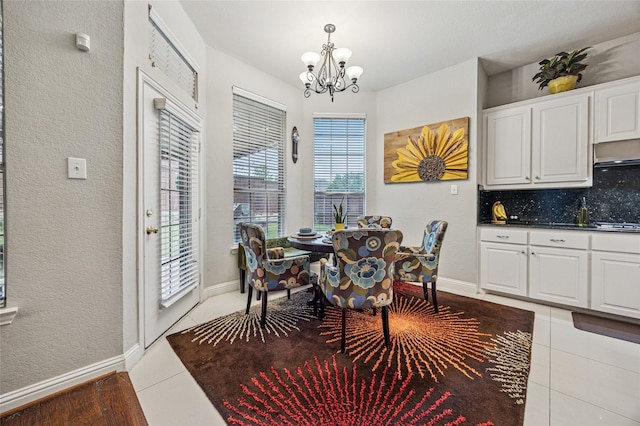 dining area featuring baseboards, a notable chandelier, a textured wall, and light tile patterned floors