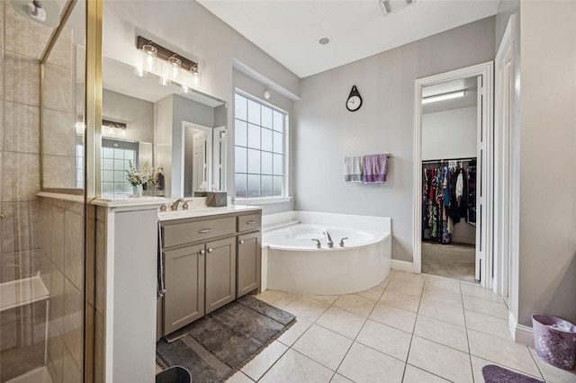 bathroom featuring a walk in closet, vanity, tile patterned floors, a shower stall, and a garden tub