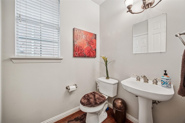 half bathroom featuring baseboards, toilet, and wood finished floors