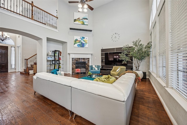 living room with plenty of natural light, a high ceiling, wood finished floors, and a premium fireplace