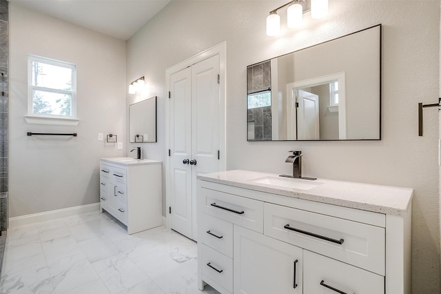 full bath with baseboards, a sink, marble finish floor, and two vanities