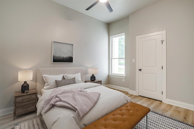 bedroom with light wood-style floors, a ceiling fan, and baseboards