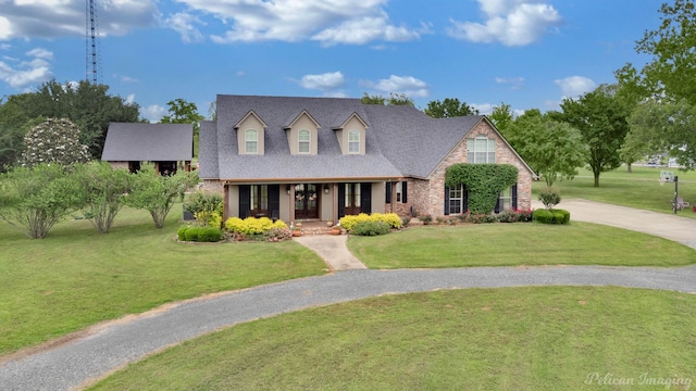 cape cod house with a porch, roof with shingles, curved driveway, and a front yard