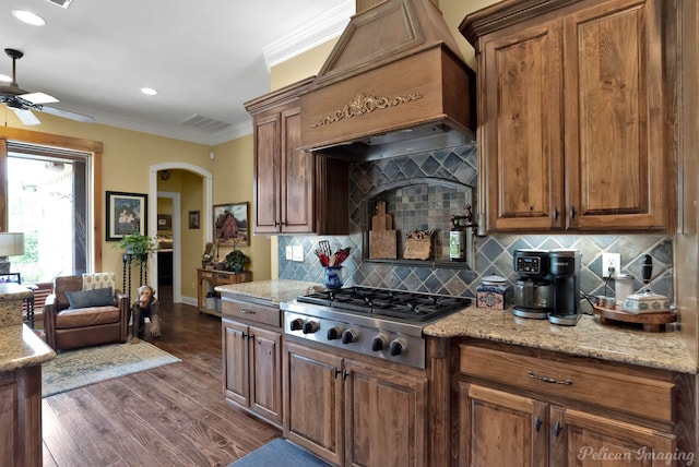 kitchen with ornamental molding, arched walkways, custom range hood, a ceiling fan, and stainless steel gas stovetop