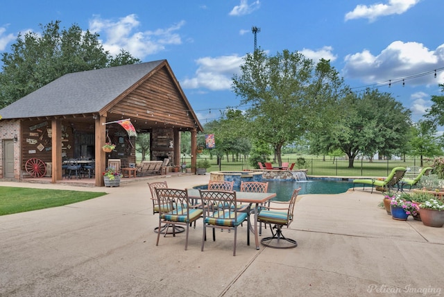 view of patio featuring fence, outdoor dining space, and a pool with connected hot tub
