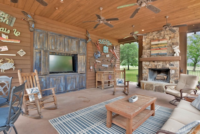 carpeted living area with wooden walls, ceiling fan, an outdoor stone fireplace, and wood ceiling