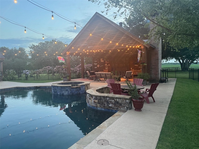 view of pool with a lawn, a pool with connected hot tub, a fenced backyard, a patio, and a fire pit