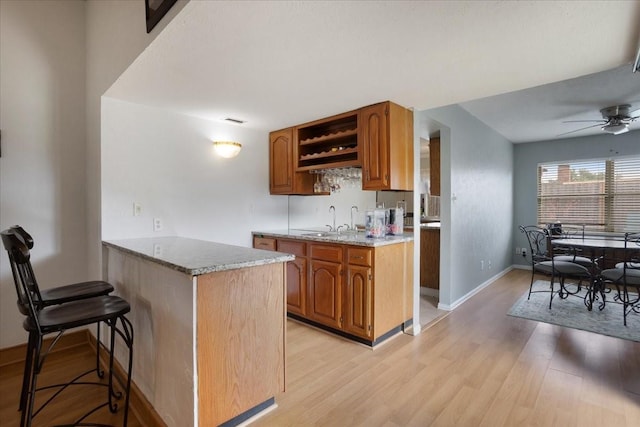 2231 E Peters Colony Rd, Carrollton, TX 75007 - kitchen with open shelves, a sink, light wood-type flooring, a peninsula, and a breakfast bar
