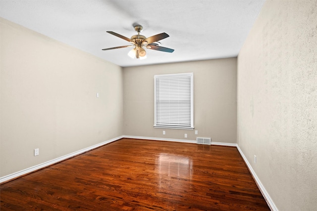 spare room featuring visible vents, baseboards, ceiling fan, and wood finished floors