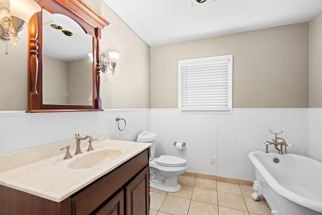 full bath featuring a freestanding bath, vanity, wainscoting, and tile patterned floors