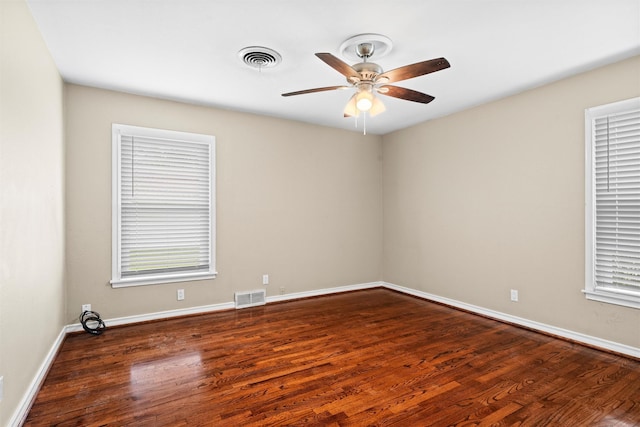 empty room featuring baseboards, visible vents, and wood finished floors