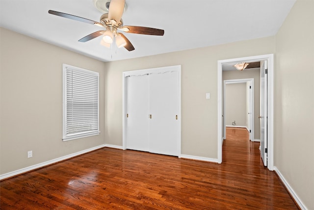 unfurnished bedroom with baseboards, ceiling fan, wood finished floors, and a closet