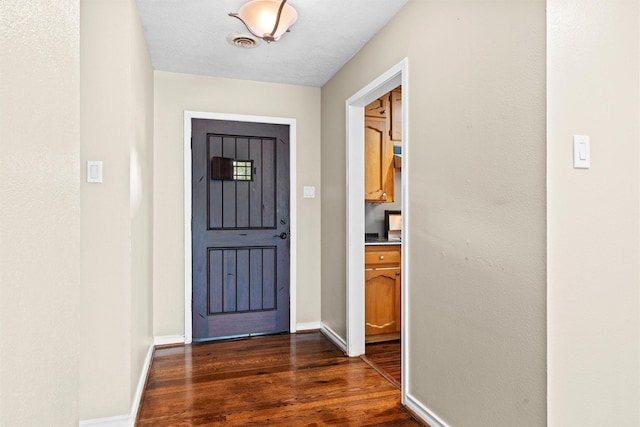 entryway featuring dark wood-type flooring, baseboards, and visible vents