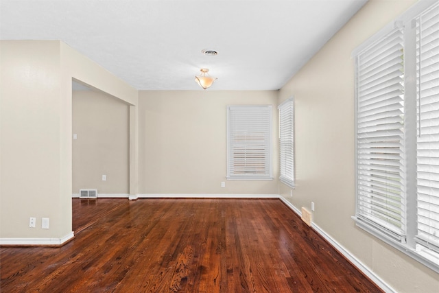 spare room featuring baseboards, visible vents, and wood finished floors