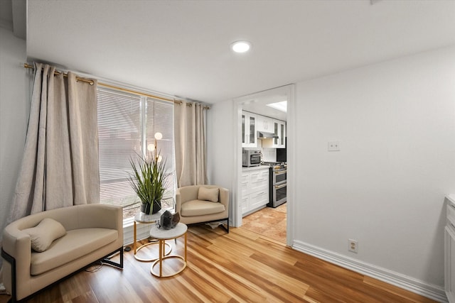 living area with light wood-type flooring, recessed lighting, and baseboards