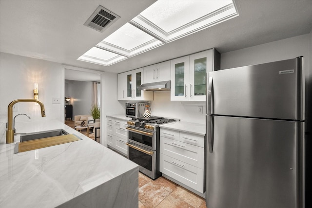 kitchen featuring visible vents, a skylight, stainless steel appliances, a sink, and under cabinet range hood